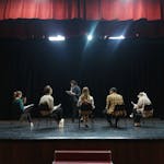 A group of actors rehearsing on stage under spotlights, creating an immersive theater experience.