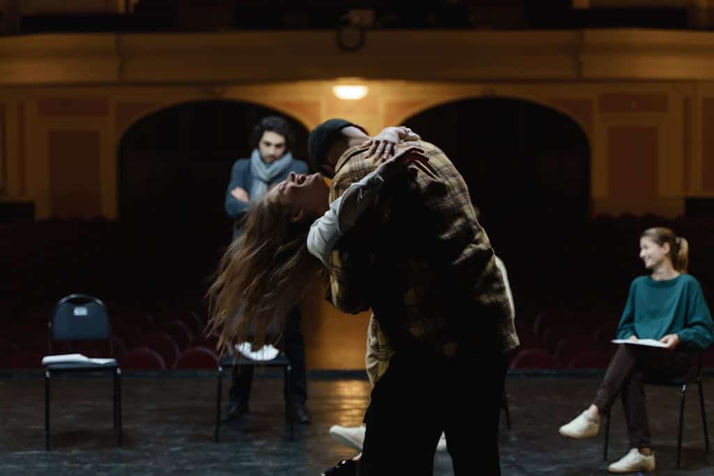 Actors in a dramatic rehearsal on a theater stage, showcasing emotion and performance.